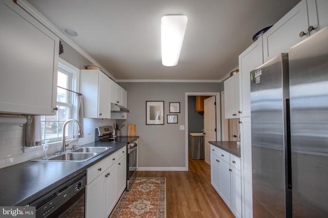 kitchen featuring appliances with stainless steel finishes, white cabinetry, a sink, and wood finished floors