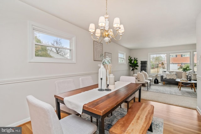 dining area with an inviting chandelier, light wood-style flooring, and baseboards