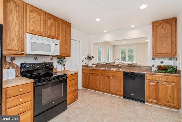 kitchen featuring decorative backsplash, recessed lighting, black appliances, and a sink