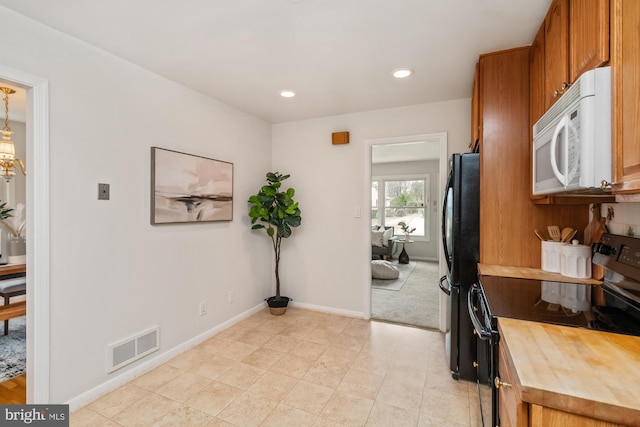 kitchen featuring visible vents, baseboards, butcher block counters, recessed lighting, and black appliances