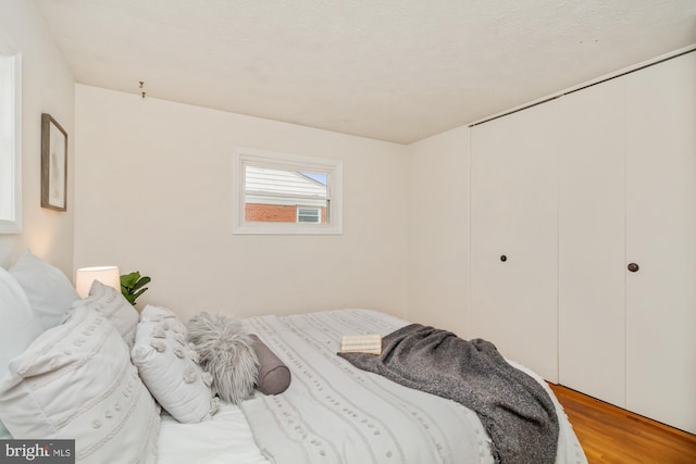 bedroom with light wood finished floors, a textured ceiling, and a closet