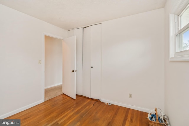 unfurnished bedroom featuring a closet, baseboards, and wood finished floors