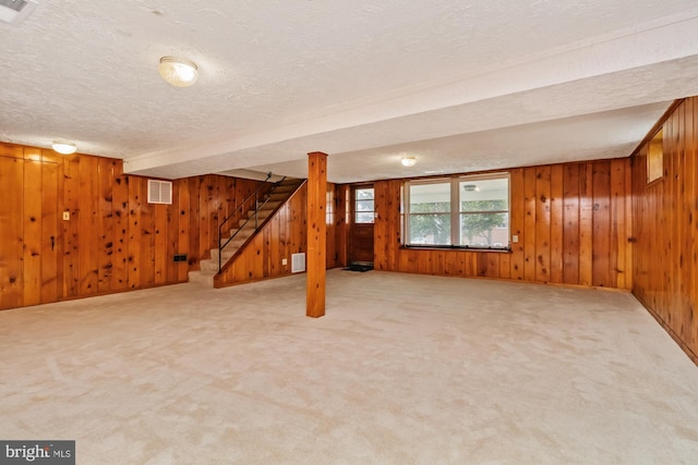 basement with visible vents, stairway, a textured ceiling, and carpet floors