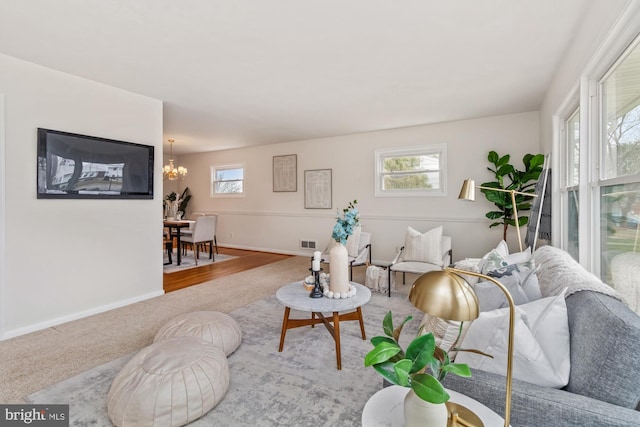 living area with a wealth of natural light, visible vents, baseboards, and an inviting chandelier