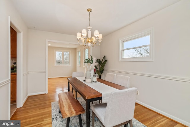 dining space with an inviting chandelier, baseboards, and light wood-type flooring