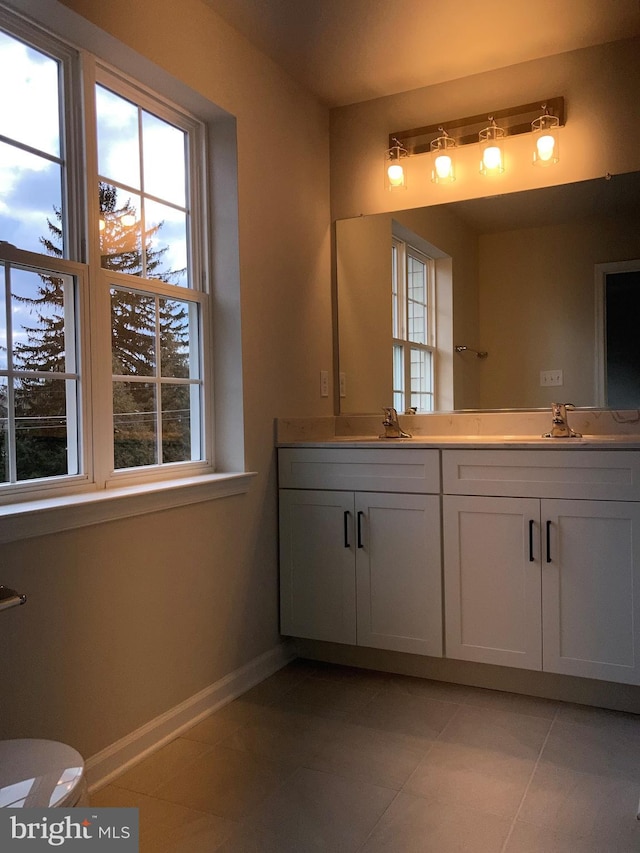 bathroom with a sink, a wealth of natural light, and baseboards