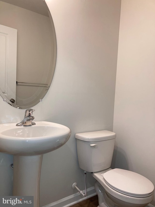 half bath with a sink, toilet, and baseboards