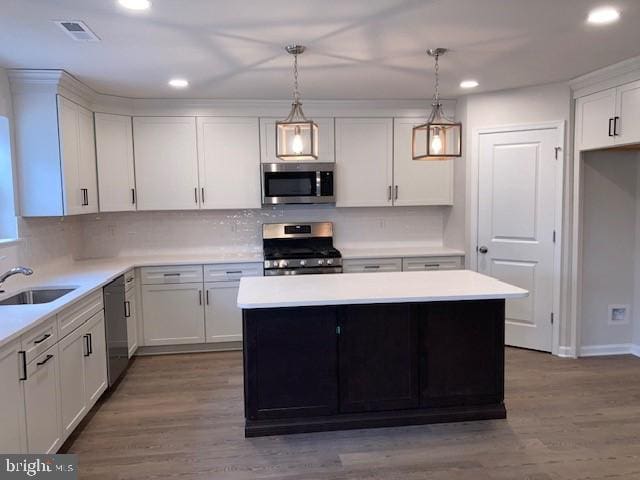 kitchen featuring visible vents, wood finished floors, light countertops, stainless steel appliances, and a sink