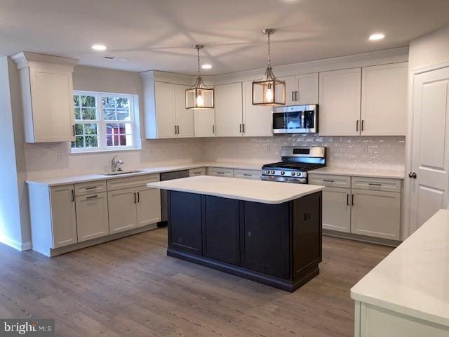 kitchen featuring stainless steel appliances, white cabinets, light countertops, and a sink