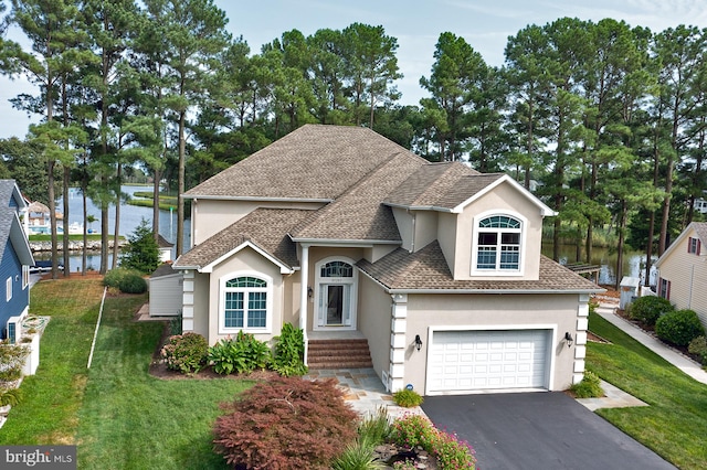 view of front of home with driveway, a garage, stucco siding, a water view, and a front yard