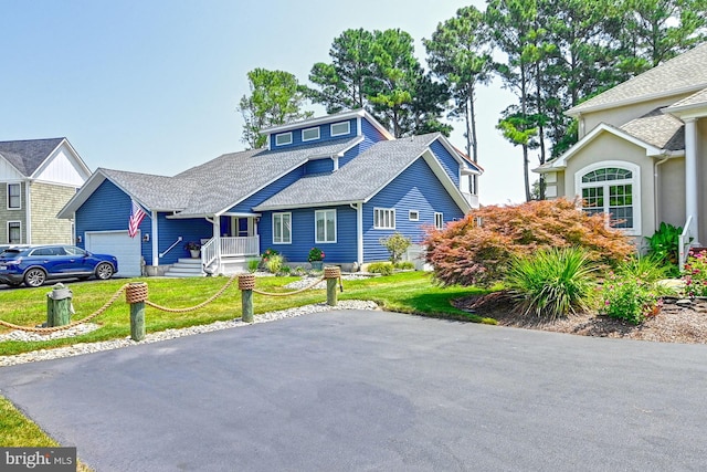 view of front of property featuring a garage, a front lawn, and roof with shingles