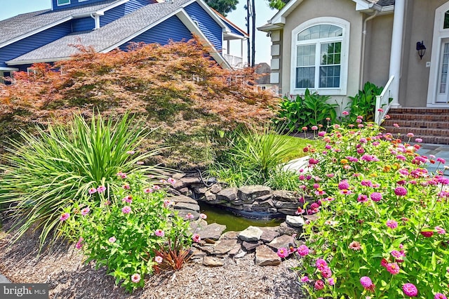 view of side of property with a small pond and stucco siding