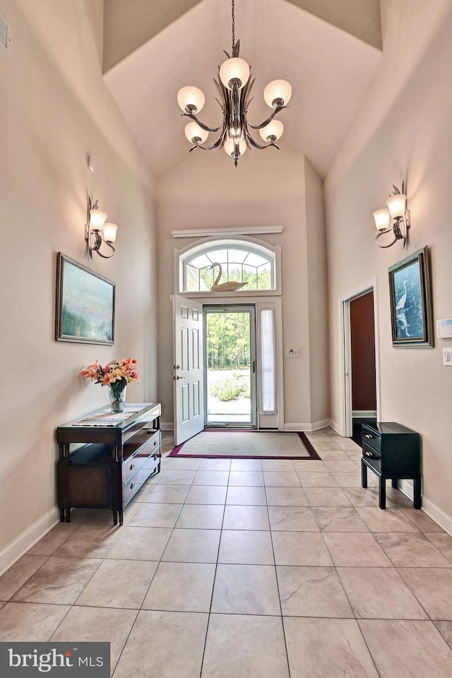 entrance foyer with an inviting chandelier, light tile patterned floors, baseboards, and high vaulted ceiling