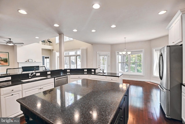 kitchen featuring a spacious island, a fireplace, a sink, appliances with stainless steel finishes, and dark wood-style floors