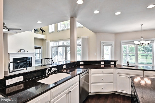 kitchen with a fireplace, dishwasher, a sink, and white cabinetry