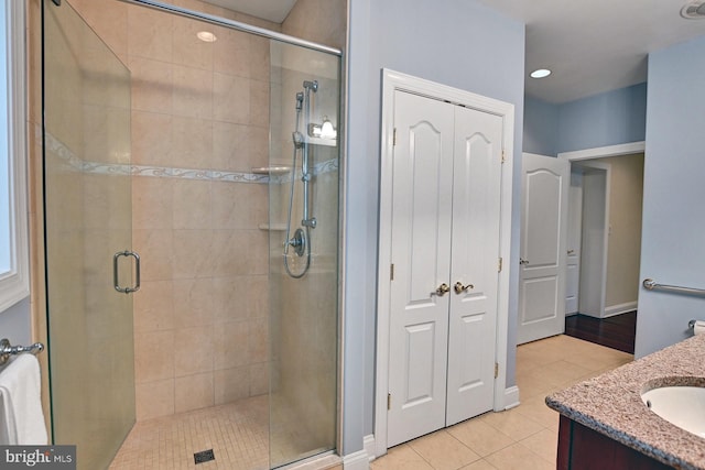 full bath with a stall shower, vanity, baseboards, and tile patterned floors