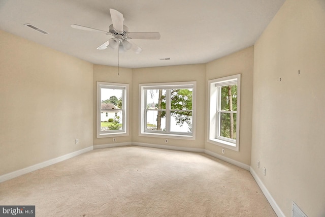 empty room with baseboards, a ceiling fan, visible vents, and light colored carpet