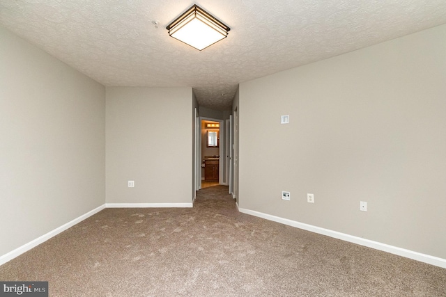 carpeted spare room with a textured ceiling and baseboards