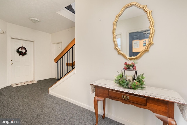 carpeted entrance foyer with stairway and baseboards