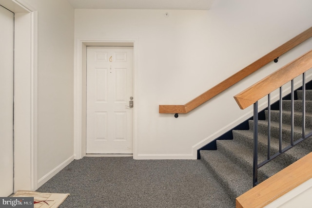 entryway featuring stairs, dark colored carpet, and baseboards