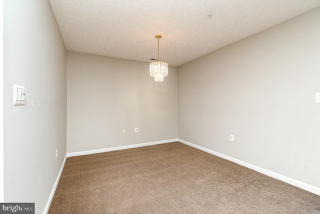 spare room with carpet, baseboards, a chandelier, and a textured ceiling