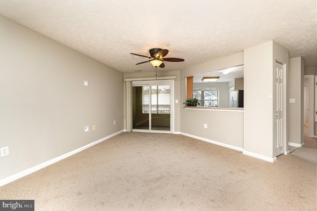 carpeted spare room with a textured ceiling, a ceiling fan, and baseboards