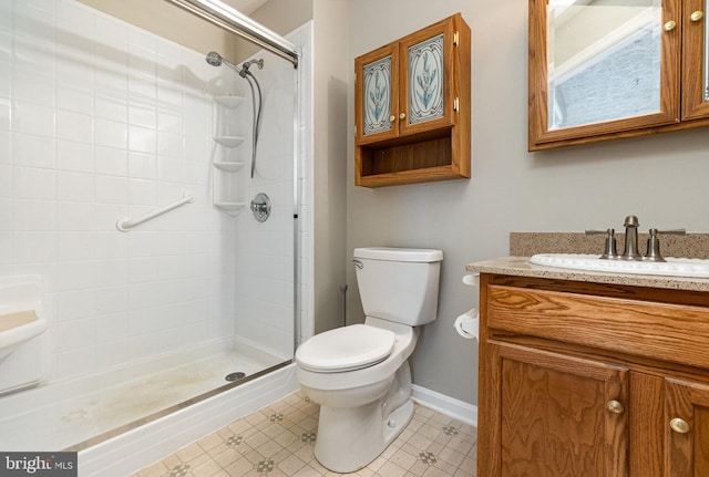 bathroom featuring toilet, a shower stall, baseboards, and vanity