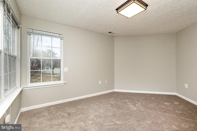 empty room featuring baseboards, a textured ceiling, visible vents, and carpet flooring