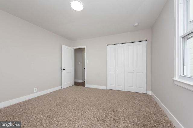 unfurnished bedroom with carpet, a closet, and baseboards