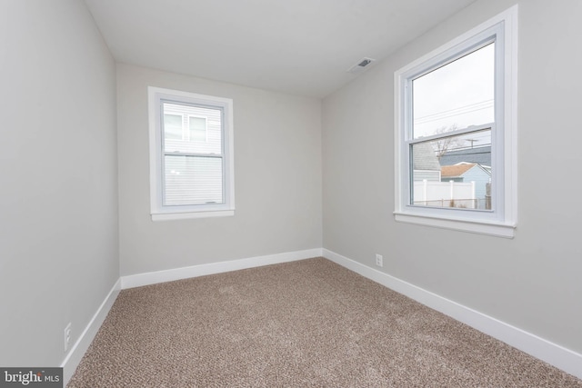 carpeted spare room with visible vents and baseboards