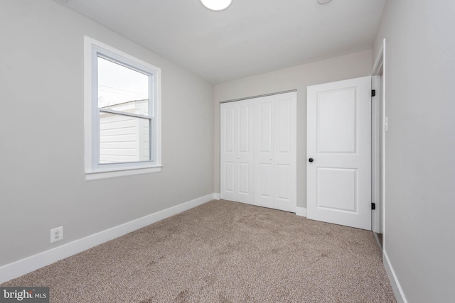 unfurnished bedroom featuring a closet, baseboards, and carpet flooring