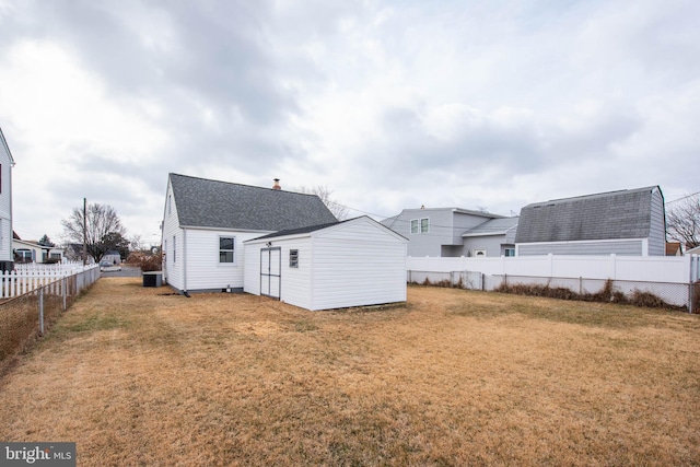 back of house with a shingled roof, a fenced backyard, a yard, and central air condition unit