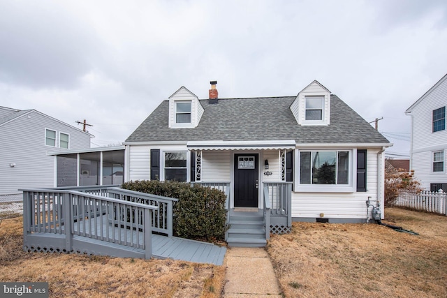 cape cod-style house with a front lawn, roof with shingles, a porch, and fence