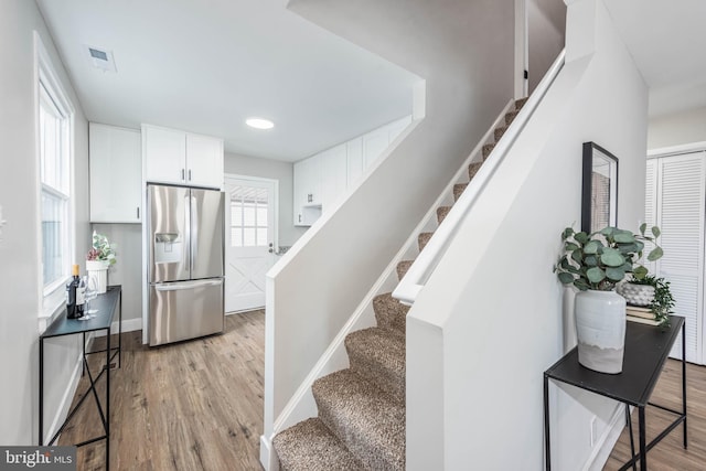 stairway featuring visible vents, baseboards, and wood finished floors