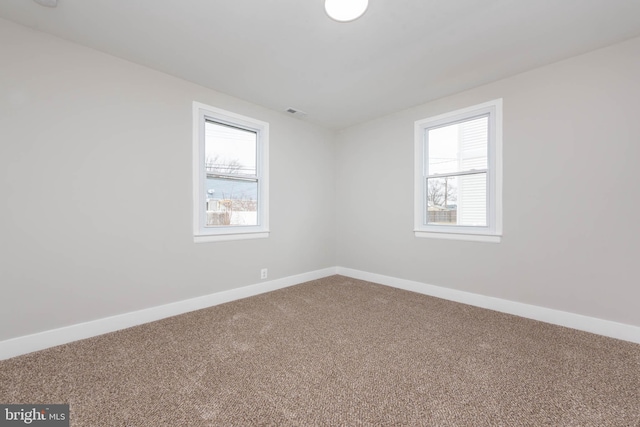 empty room with plenty of natural light, carpet, visible vents, and baseboards