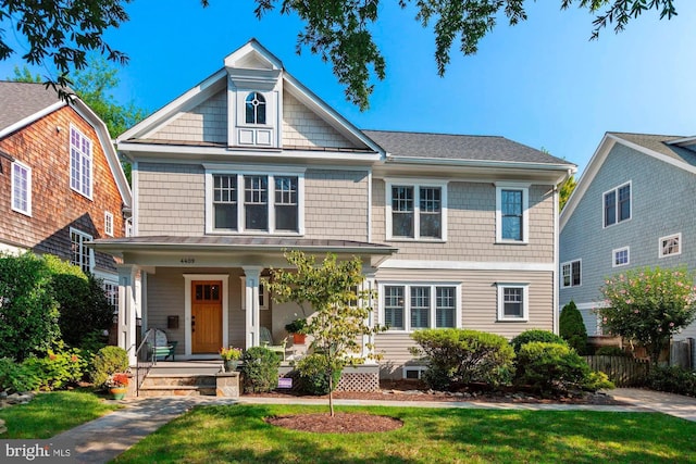 view of front of house featuring a porch, a front yard, and fence