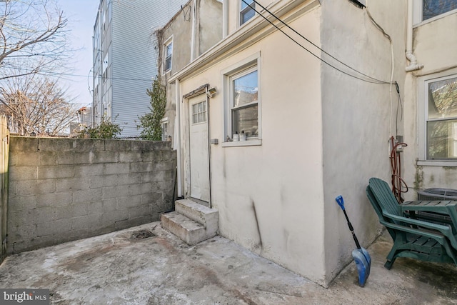 view of side of home featuring entry steps, fence, and stucco siding