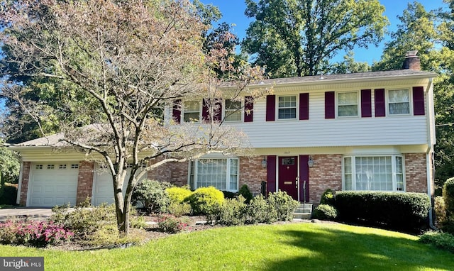 colonial inspired home featuring driveway, a front lawn, a garage, brick siding, and a chimney