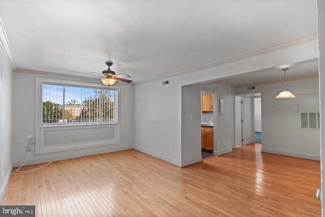 unfurnished living room with ceiling fan, light wood-style flooring, visible vents, baseboards, and crown molding