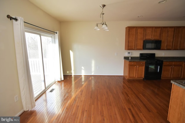 kitchen featuring brown cabinetry, dark countertops, visible vents, and black appliances