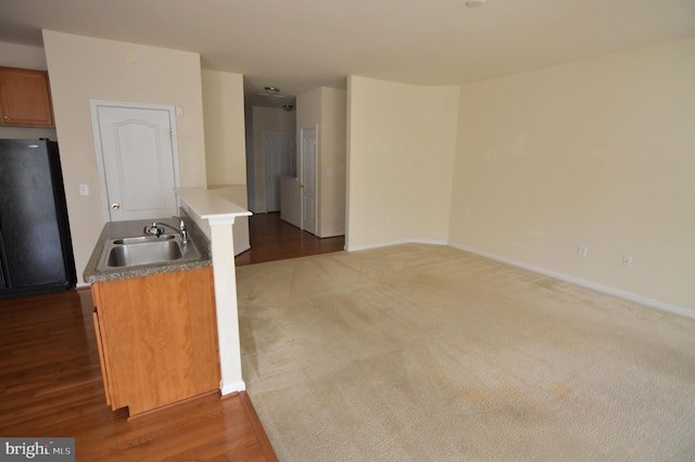 kitchen with brown cabinetry, a sink, freestanding refrigerator, and baseboards