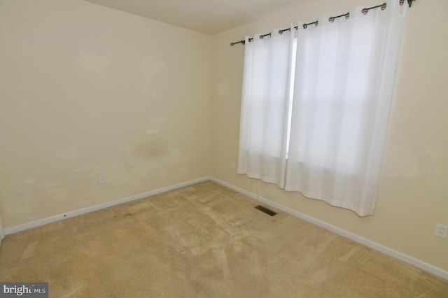 carpeted empty room featuring baseboards and visible vents