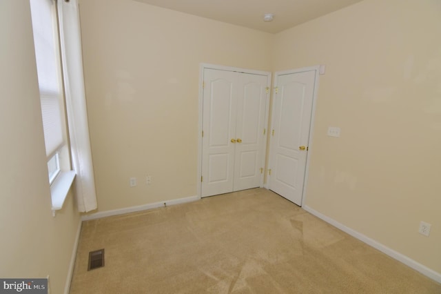 empty room featuring carpet, visible vents, and baseboards