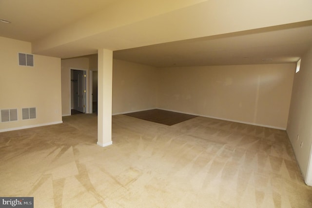 finished below grade area featuring light carpet, visible vents, and baseboards