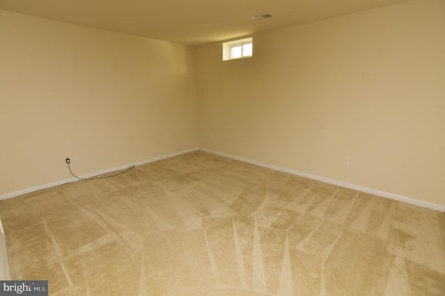 basement with light carpet, visible vents, and baseboards