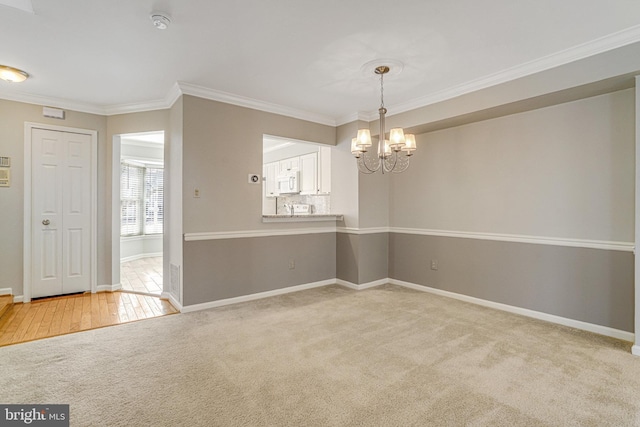 carpeted spare room with a chandelier, baseboards, and crown molding