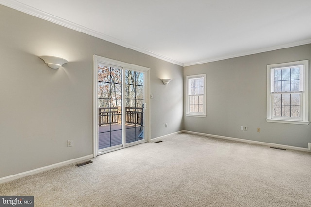 carpeted spare room featuring baseboards, visible vents, and crown molding