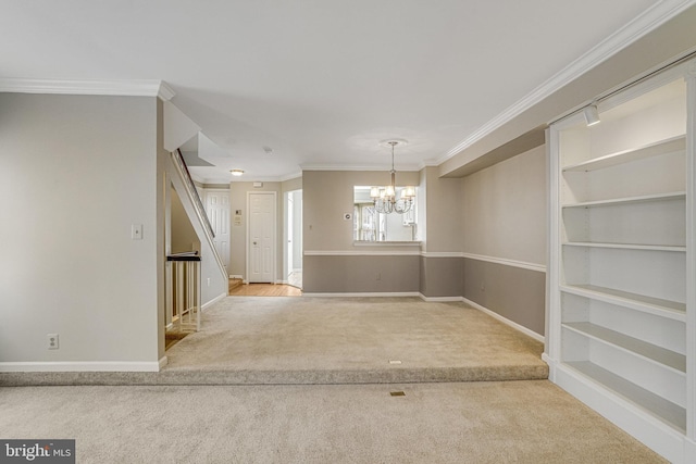 unfurnished dining area with carpet floors, baseboards, ornamental molding, and a notable chandelier