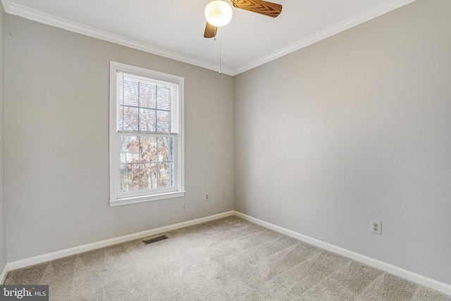 carpeted empty room with ornamental molding, a ceiling fan, visible vents, and baseboards