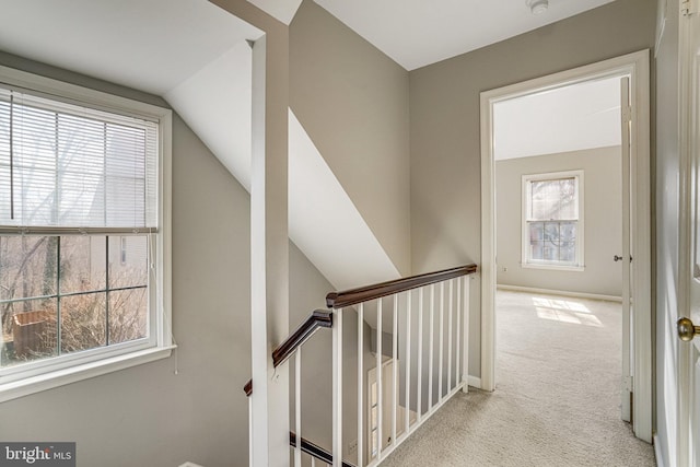 hall featuring vaulted ceiling, carpet, an upstairs landing, and baseboards